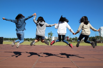 Four Girls jumping while holding hands